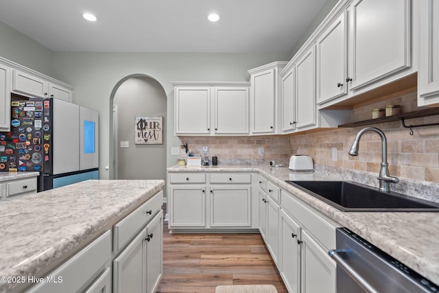 kitchen with dishwasher, a sink, light countertops, white cabinets, and freestanding refrigerator
