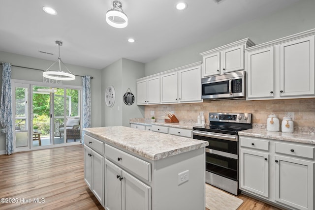 kitchen with a center island, light wood-style flooring, appliances with stainless steel finishes, and tasteful backsplash
