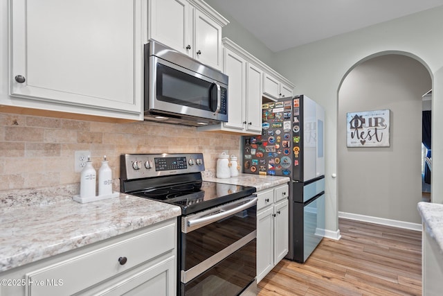 kitchen featuring tasteful backsplash, baseboards, white cabinets, stainless steel appliances, and light wood-style flooring