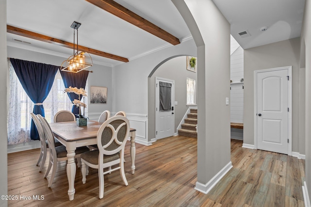 dining space featuring visible vents, arched walkways, stairs, and beamed ceiling