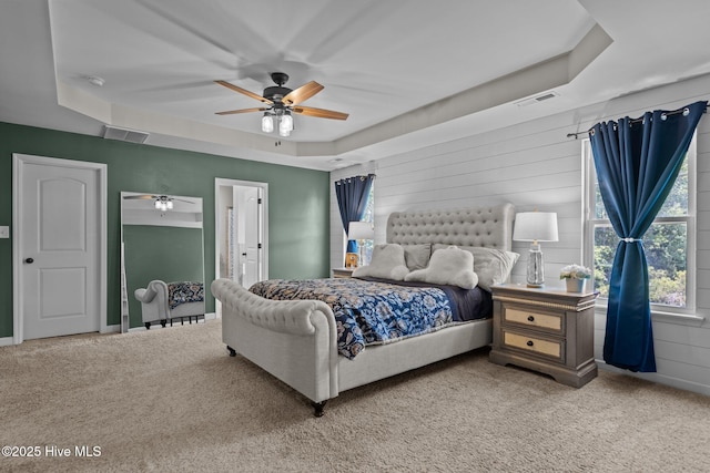 carpeted bedroom with a raised ceiling, ceiling fan, baseboards, and visible vents