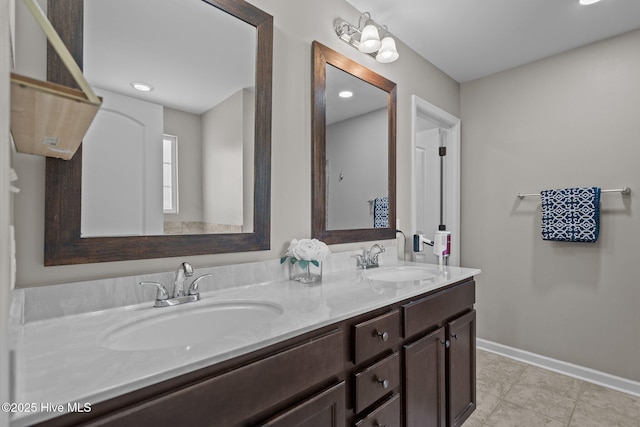 full bath featuring a sink, baseboards, tile patterned floors, and double vanity