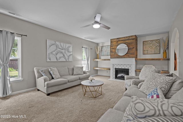 living room with carpet floors, baseboards, visible vents, and a tiled fireplace
