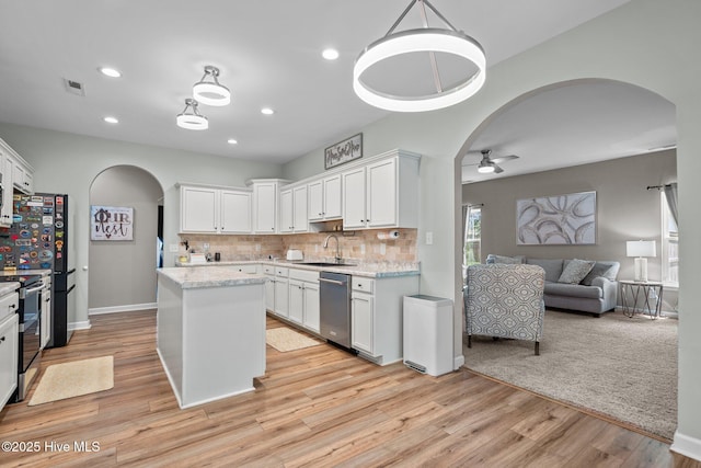 kitchen with a sink, arched walkways, a ceiling fan, white cabinetry, and stainless steel appliances