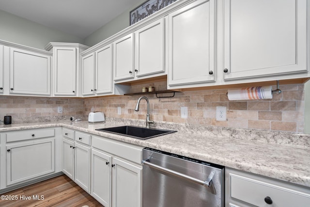kitchen with a sink, white cabinets, stainless steel dishwasher, and tasteful backsplash