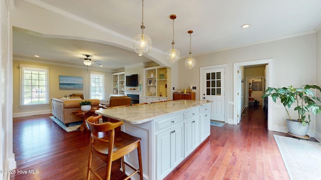 kitchen with dark wood-style flooring, light stone counters, and ornamental molding