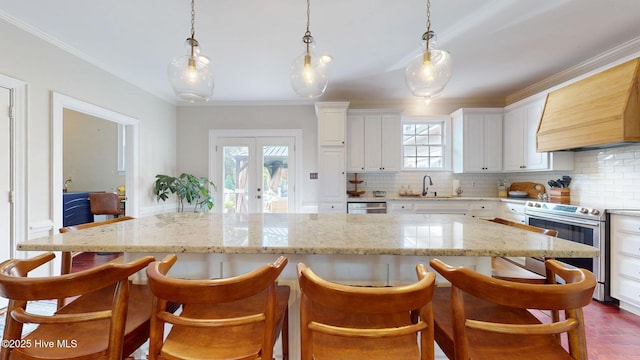 kitchen with white cabinets, tasteful backsplash, custom range hood, a sink, and appliances with stainless steel finishes