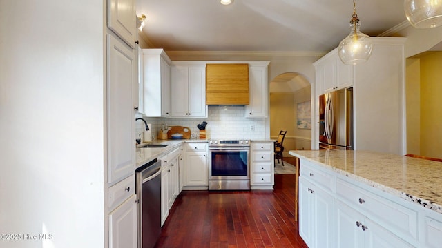 kitchen featuring stainless steel appliances, arched walkways, white cabinetry, and a sink
