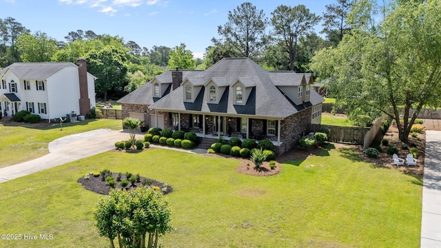 cape cod home with covered porch, driveway, brick siding, fence, and a front lawn