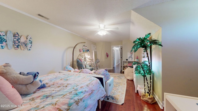 bedroom featuring visible vents, crown molding, ceiling fan, dark wood-type flooring, and a textured ceiling