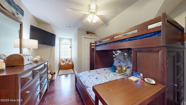 bedroom with a textured ceiling, visible vents, dark wood finished floors, and lofted ceiling