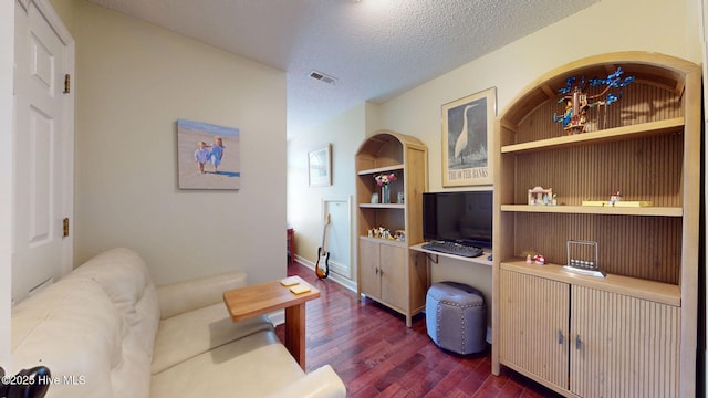 living area with a textured ceiling, visible vents, built in features, baseboards, and dark wood-type flooring