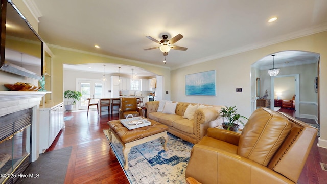 living area featuring a ceiling fan, a fireplace with flush hearth, dark wood-type flooring, recessed lighting, and arched walkways