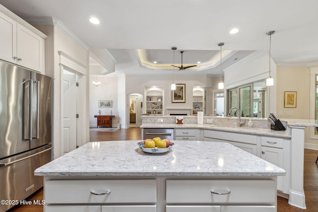 kitchen featuring a sink, ornamental molding, arched walkways, a center island, and high end refrigerator