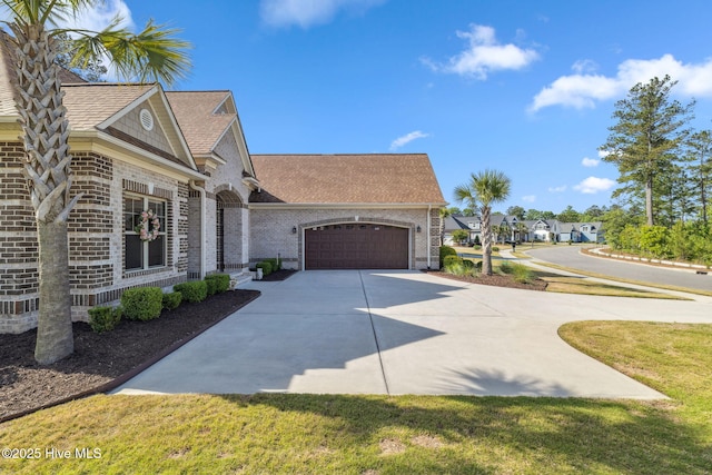 view of side of home featuring a garage, concrete driveway, a shingled roof, and brick siding