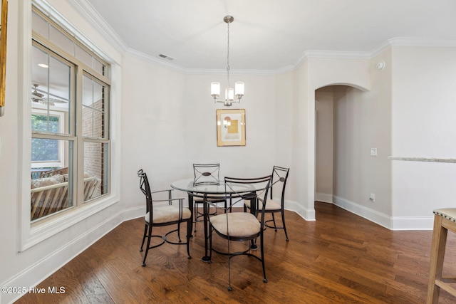 dining area featuring crown molding, arched walkways, baseboards, and wood finished floors