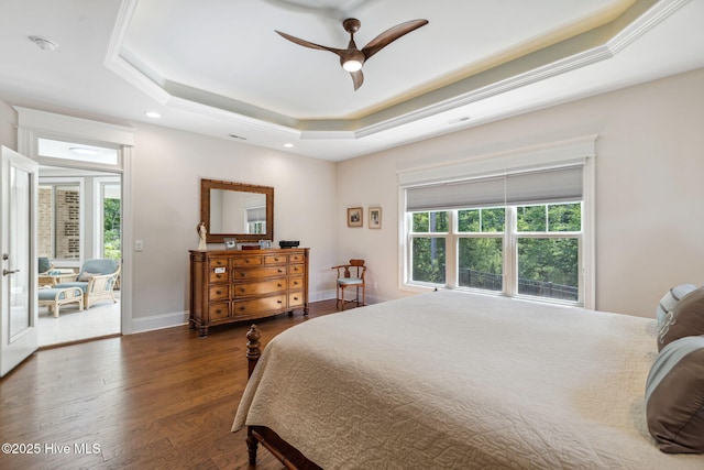 bedroom with multiple windows, wood finished floors, a raised ceiling, and recessed lighting
