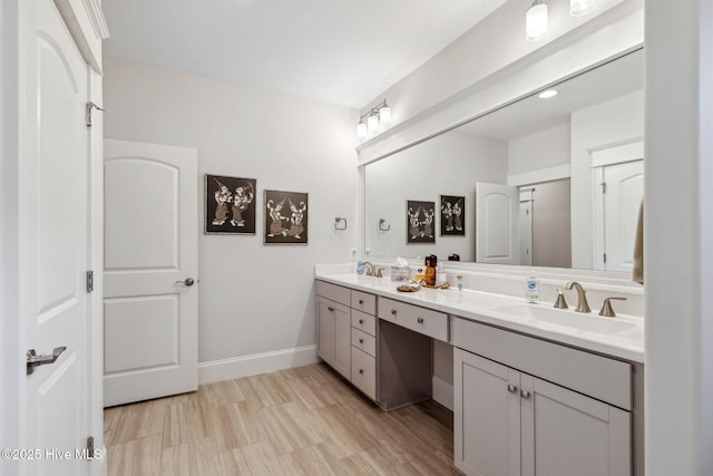 full bathroom with double vanity, baseboards, and a sink