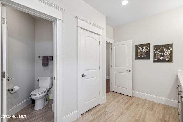 bathroom with toilet, baseboards, recessed lighting, and wood finished floors