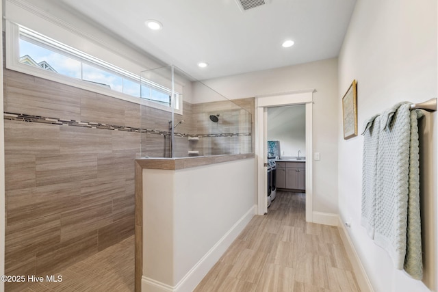full bath with walk in shower, wood finished floors, vanity, visible vents, and baseboards