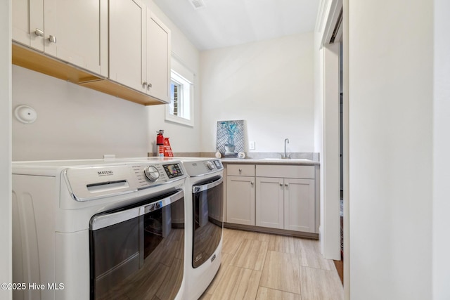 laundry room featuring separate washer and dryer, cabinet space, visible vents, and a sink