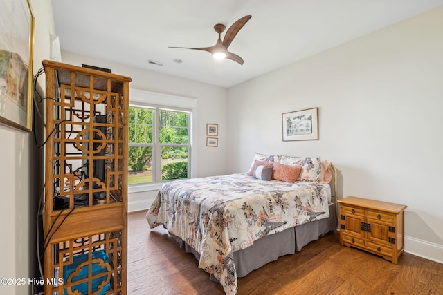 bedroom with baseboards, ceiling fan, visible vents, and wood finished floors