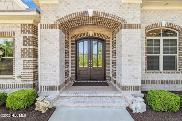 property entrance featuring brick siding and french doors