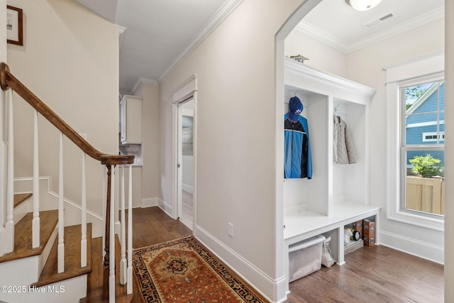 mudroom featuring wood finished floors, ornamental molding, visible vents, arched walkways, and baseboards