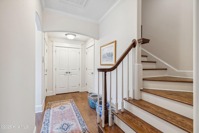 entrance foyer with wood finished floors, ornamental molding, visible vents, stairway, and arched walkways