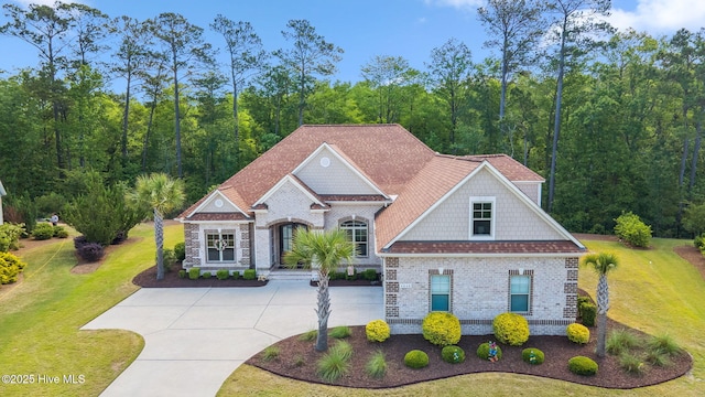 view of front of home with brick siding, a front yard, and curved driveway