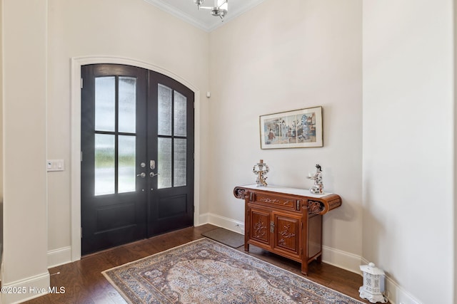 entrance foyer featuring french doors, wood finished floors, crown molding, arched walkways, and baseboards