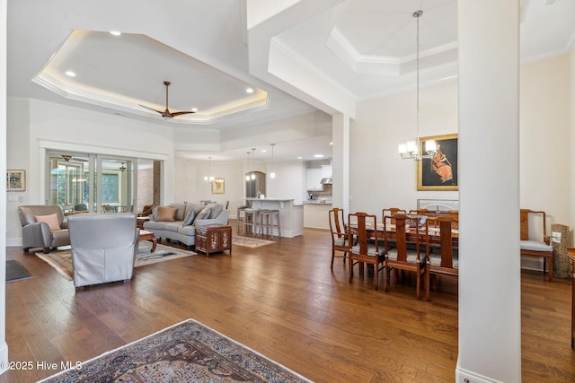 living room with a tray ceiling, an inviting chandelier, and wood finished floors