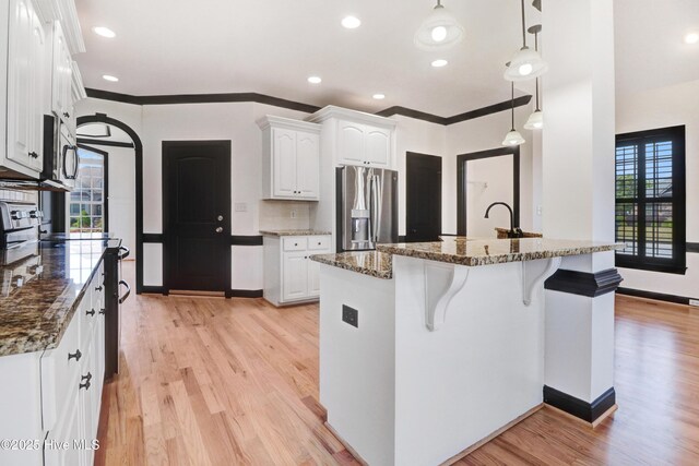 kitchen with light wood-style flooring, white cabinets, a breakfast bar, and stainless steel appliances