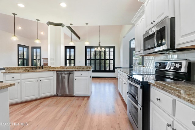 kitchen featuring a sink, light wood finished floors, a notable chandelier, stainless steel appliances, and a wealth of natural light
