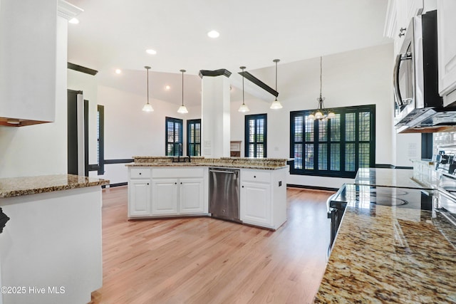 kitchen featuring appliances with stainless steel finishes, white cabinets, light stone countertops, and light wood-type flooring