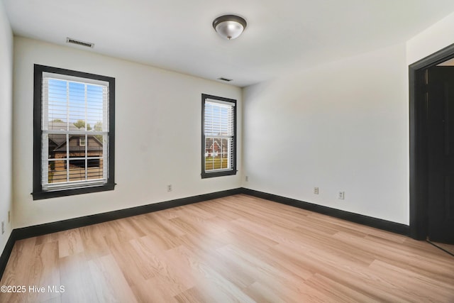 unfurnished room featuring visible vents, plenty of natural light, and light wood finished floors
