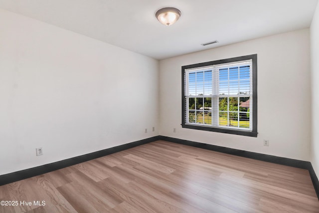 unfurnished room with baseboards, visible vents, and wood finished floors