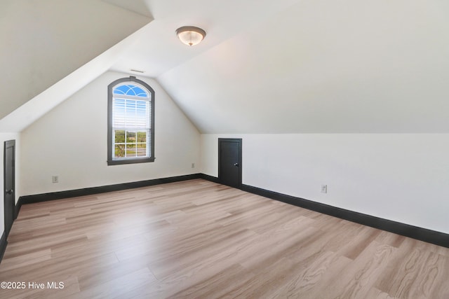 bonus room with baseboards, vaulted ceiling, and light wood-style flooring