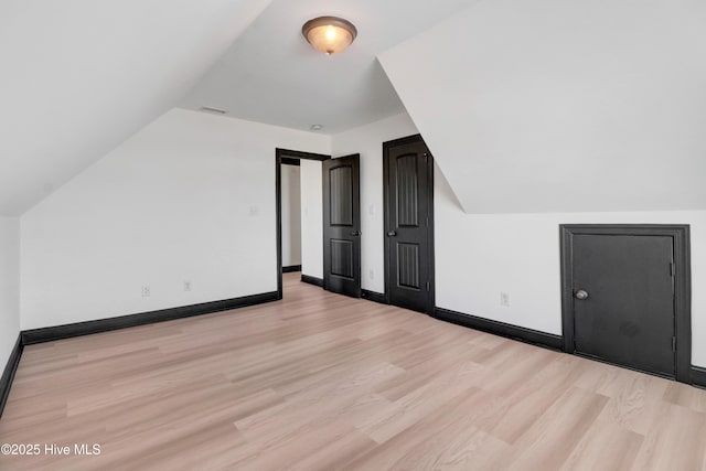 bonus room with baseboards, visible vents, lofted ceiling, and light wood-type flooring