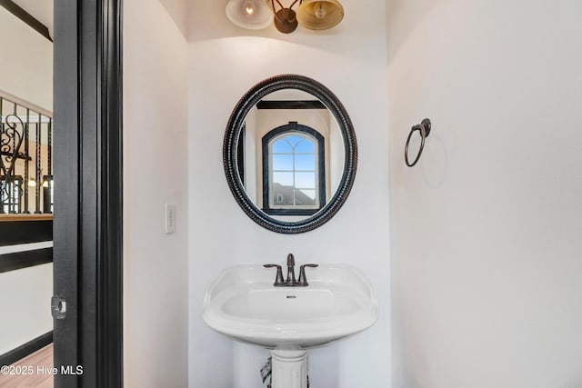 bathroom with a notable chandelier, a sink, and wood finished floors