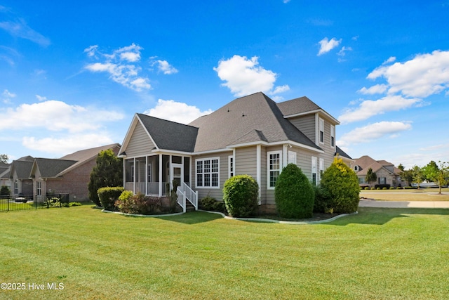 rear view of house with a lawn, fence, a sunroom, and roof with shingles