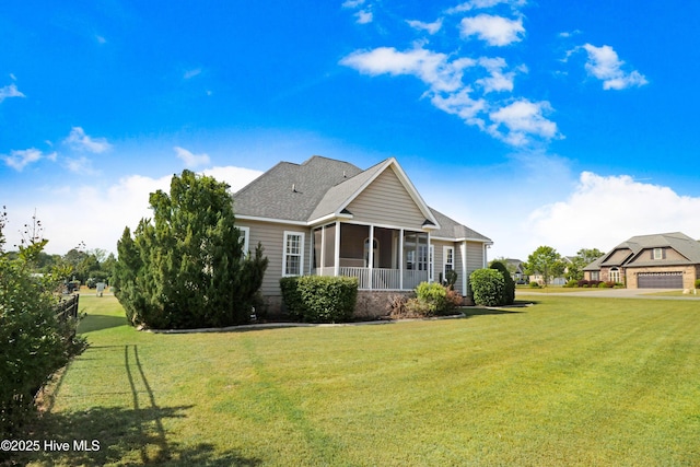 back of property with a lawn, a sunroom, and roof with shingles