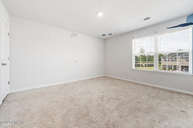 carpeted spare room featuring visible vents and baseboards