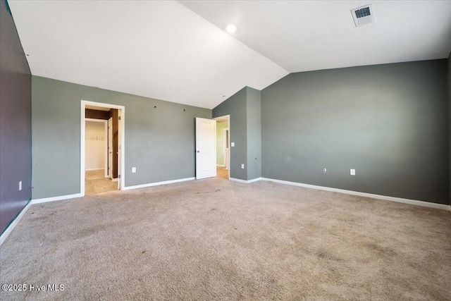 unfurnished room featuring carpet flooring, baseboards, visible vents, and vaulted ceiling