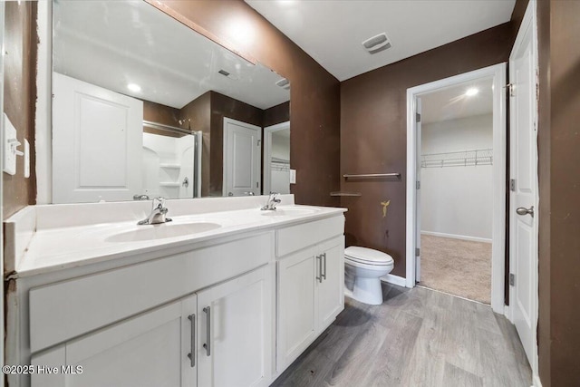 full bath with double vanity, toilet, a sink, and wood finished floors