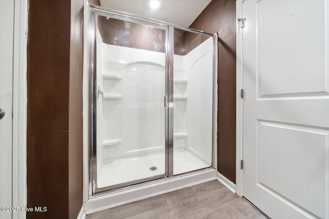 bathroom with wood finished floors and a stall shower