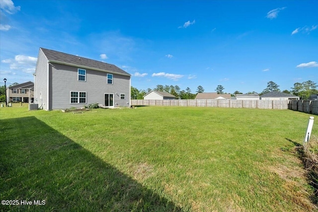 back of property with a lawn, fence, and central AC