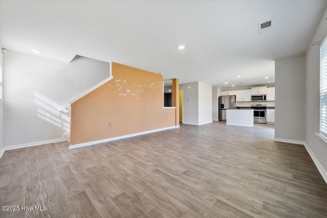 unfurnished living room featuring baseboards, recessed lighting, light wood-style flooring, and visible vents