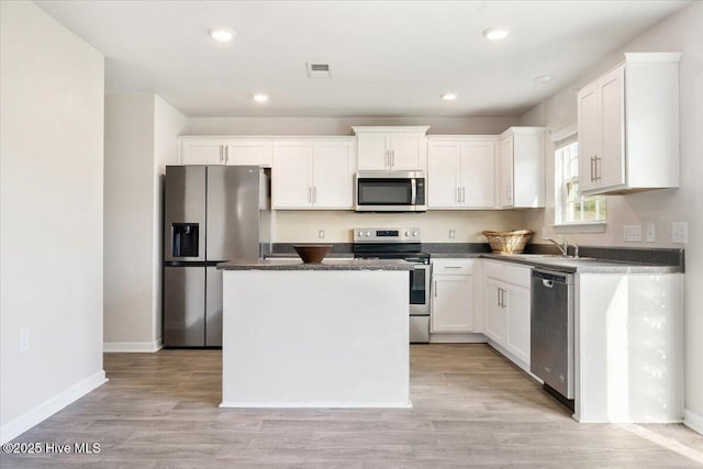 kitchen featuring visible vents, a center island, baseboards, white cabinets, and stainless steel appliances