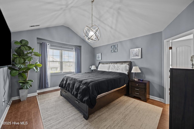 bedroom featuring a chandelier, visible vents, wood finished floors, baseboards, and lofted ceiling